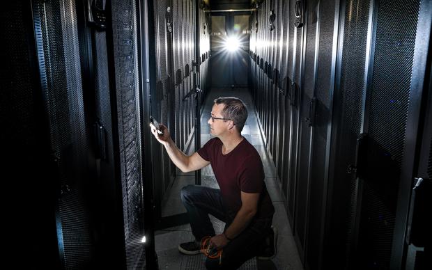 A man in a server room, checking network infrastructure